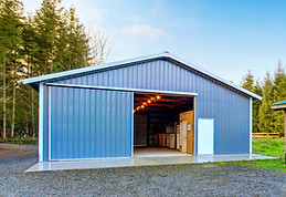 Farm blue barn shed and gravel driveway. Also dry chopped firewood logs in a pile. Northwe