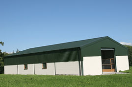 Newly constructed barn of cream painted concrete block walls with a green metal sheet roof