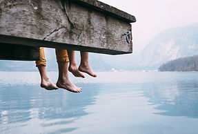 Father and son swung their legs from the wooden pier on mountain lake.jpg