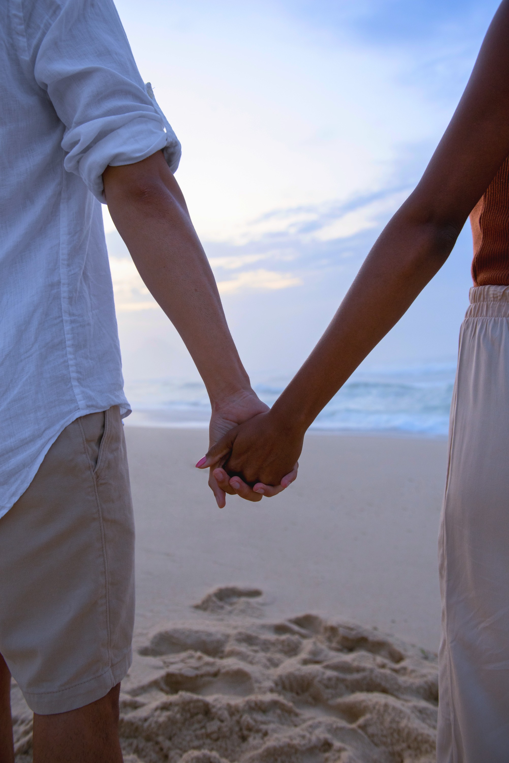 Jeune couple se tenant la main sur une plage, complice et aligné