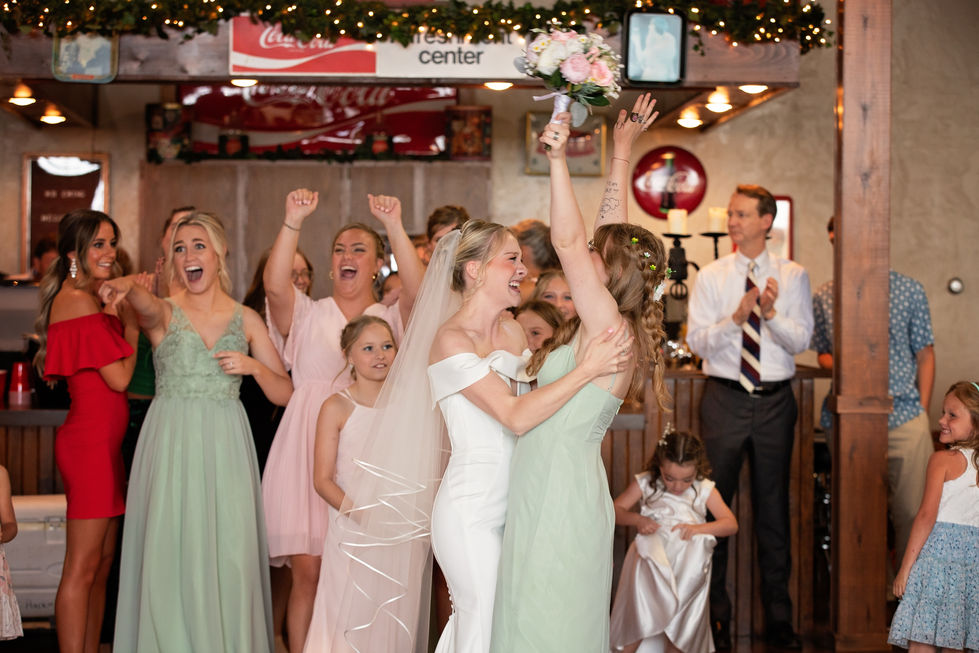 Bride and bridesmaid celebrating with bouquet toss.