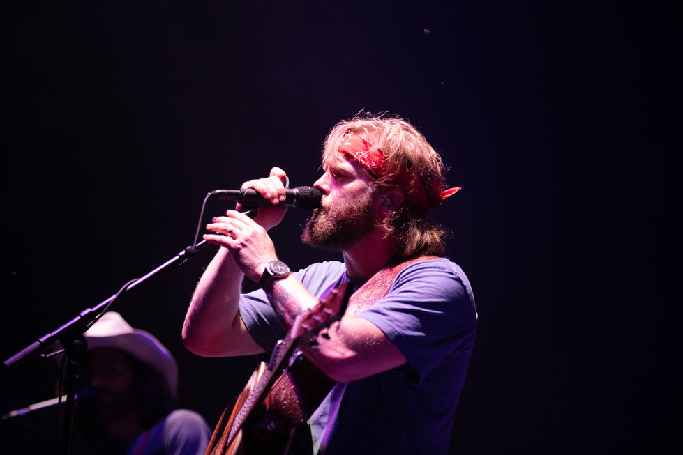 Man singing and playing guitar on stage.