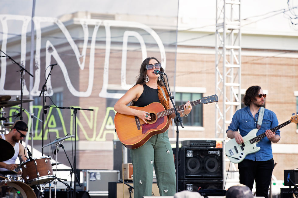 Musicians performing on an outdoor stage with instruments.