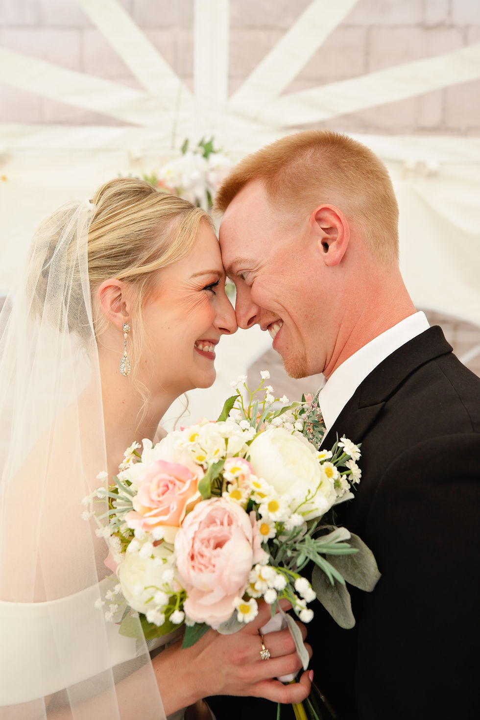 Bride and groom smiling, holding a bouquet.