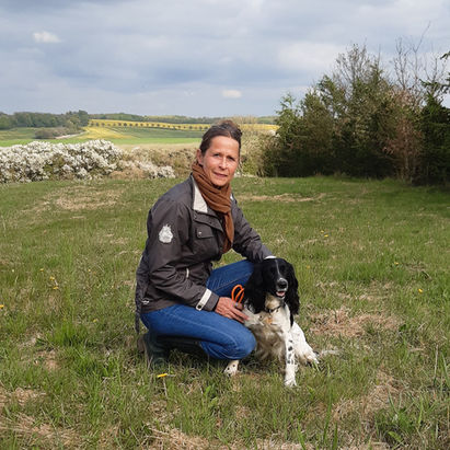 Jane Marckmann sidder på grønt græs med en springer spaniel hund