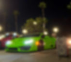 The image shows a vibrant green Lamborghini Huracán equipped with an air-suspension setup (bagged) and custom wheels parked at a night car meet.