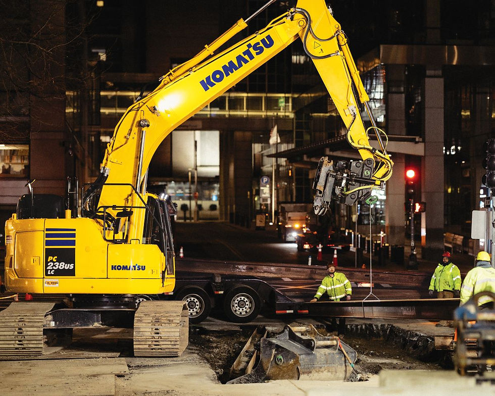 An operator lifts a beam with a Komatsu PC238USLC excavator.
