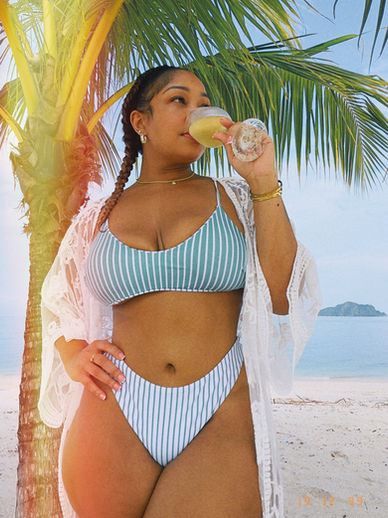 Candice Mary wearing a reversible green striped high waisted Amazon bikini set on the beach with a lightweight cover up on vacation