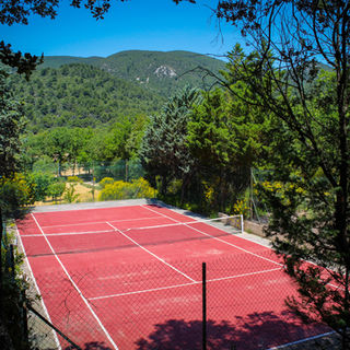 Private tennis court at La Jassine in a secluded, natural setting with panoramic views of the Luberon Massif. 