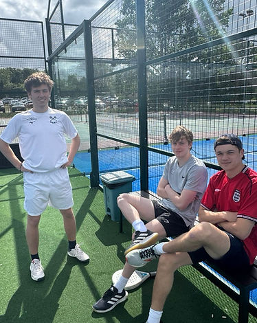 Three Oxford University Padel Club players courtside, one wearing the club shirt