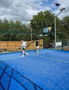 Player hitting a forehand while his partner looks on