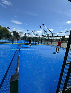 Doubles match in progress under a blue sky