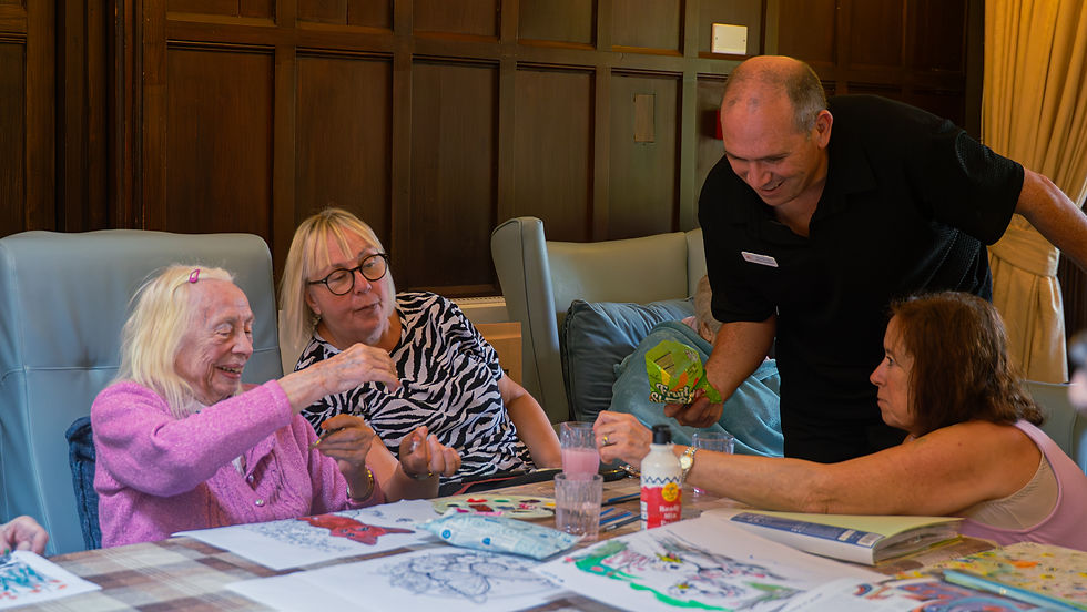 Elderly resident painting during an art activity at Allesley Hall Care Home in Coventry with family