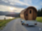 A wooden barrel sauna mounted on a trailer, ready to travel.