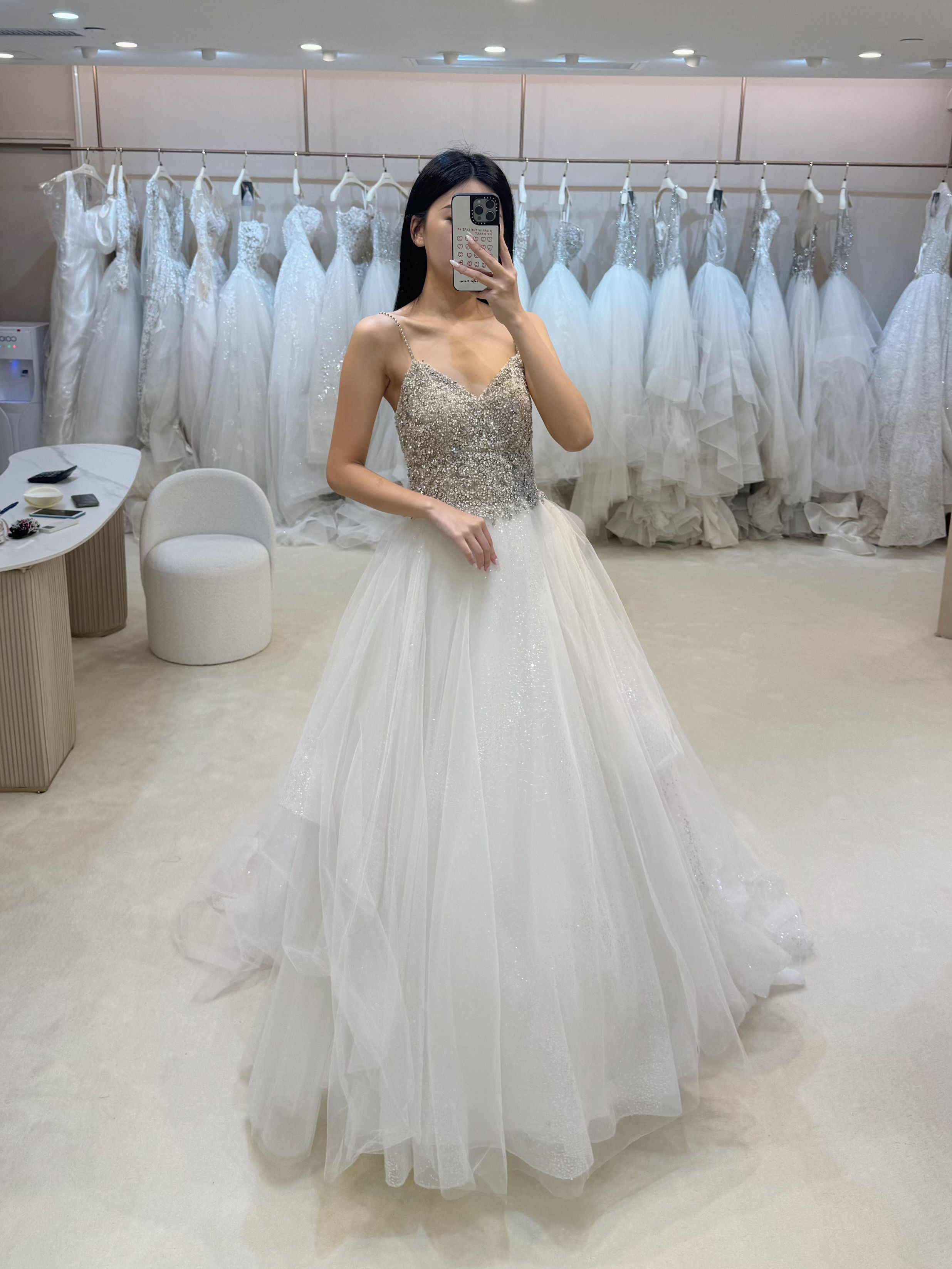 Sparkly A-line wedding dress with a sequined V-neck bodice and shimmering glitter tulle skirt in a bridal boutique.
