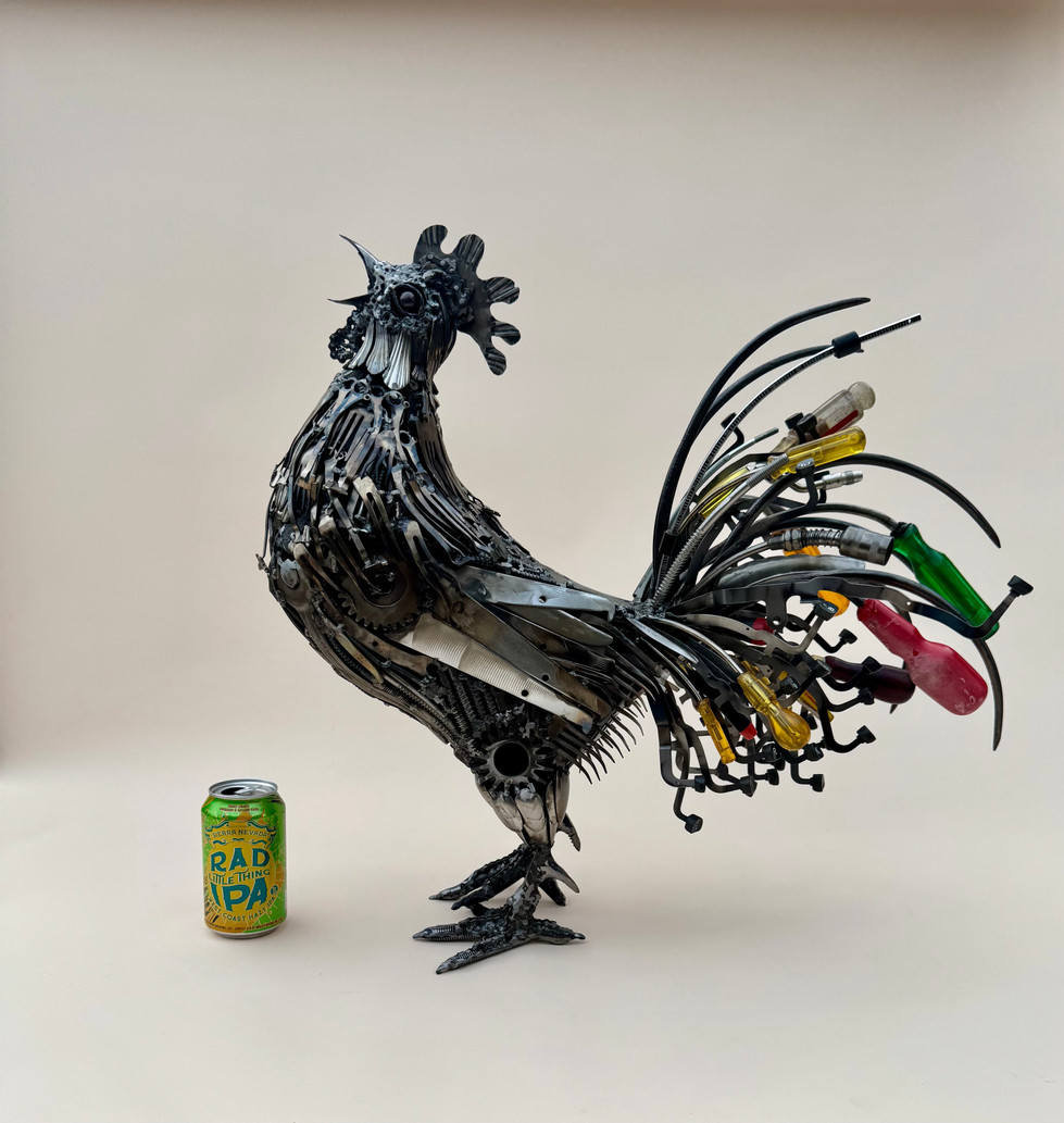 Left side view of a crowing rooster with a colorful tail made primarily of screwdrivers and typewriter keys. A beer can shows scale
