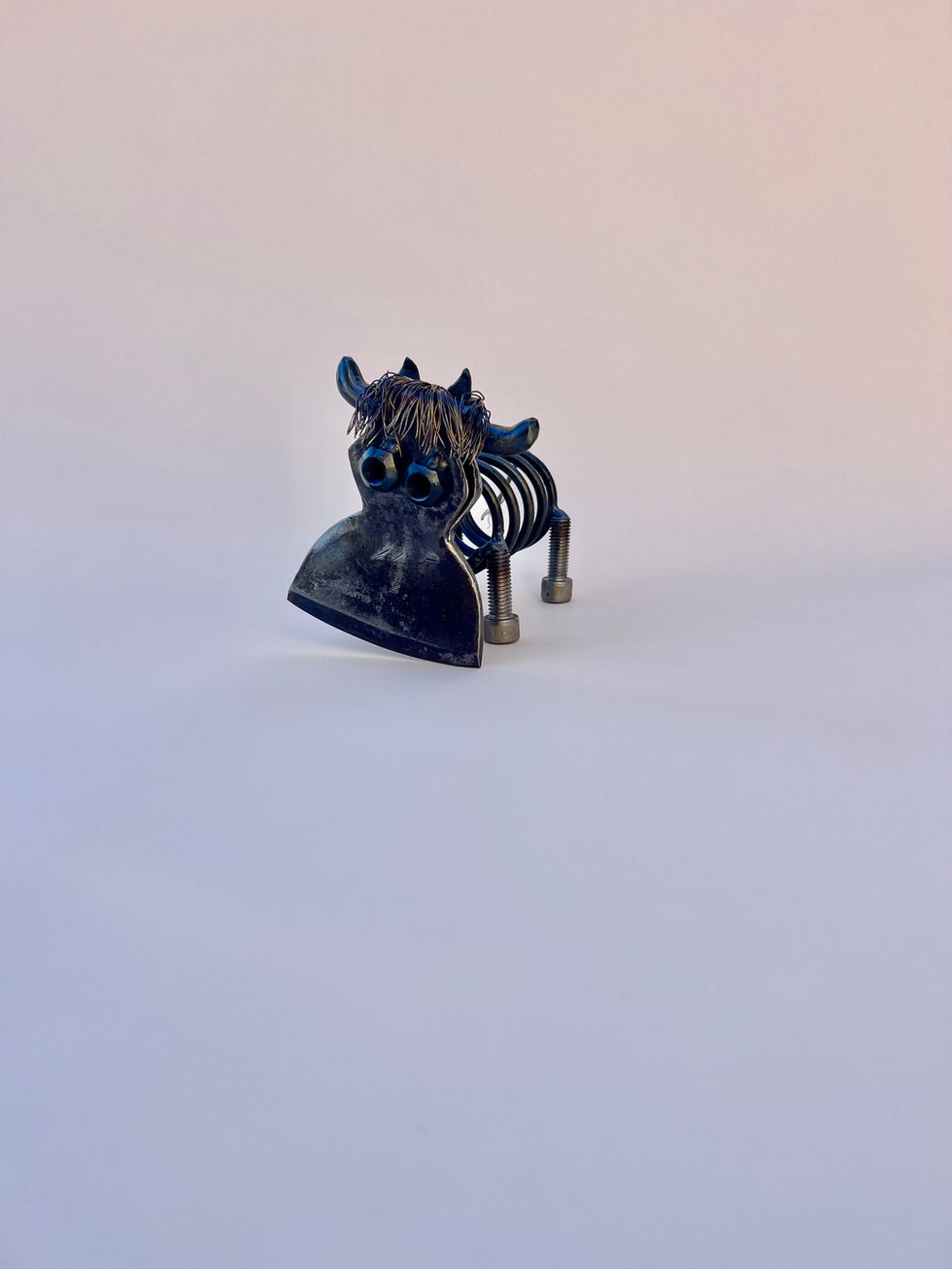 highland cow made from a spring, nuts and bolts, copper wire and the head from a hatchet