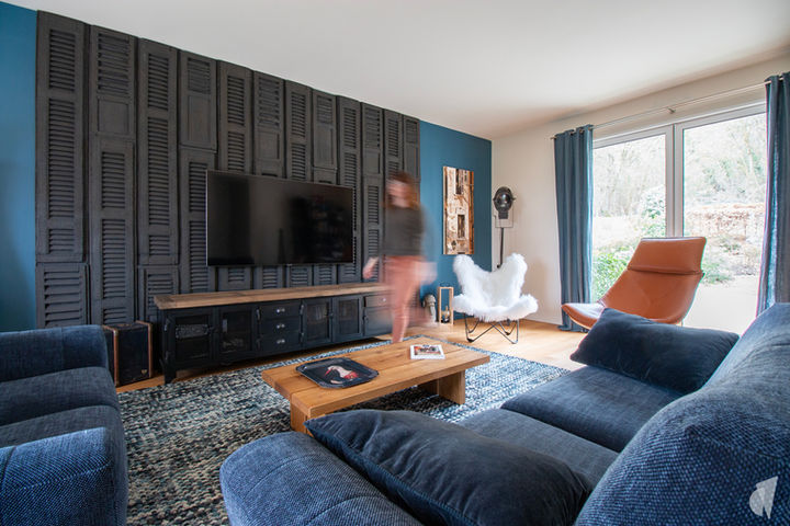 Décoration d'une pièce de vie au style industriel bleu à Aix les Bains, par Studio Coralie Vasseur : salon feutré et mur en bois brûlé