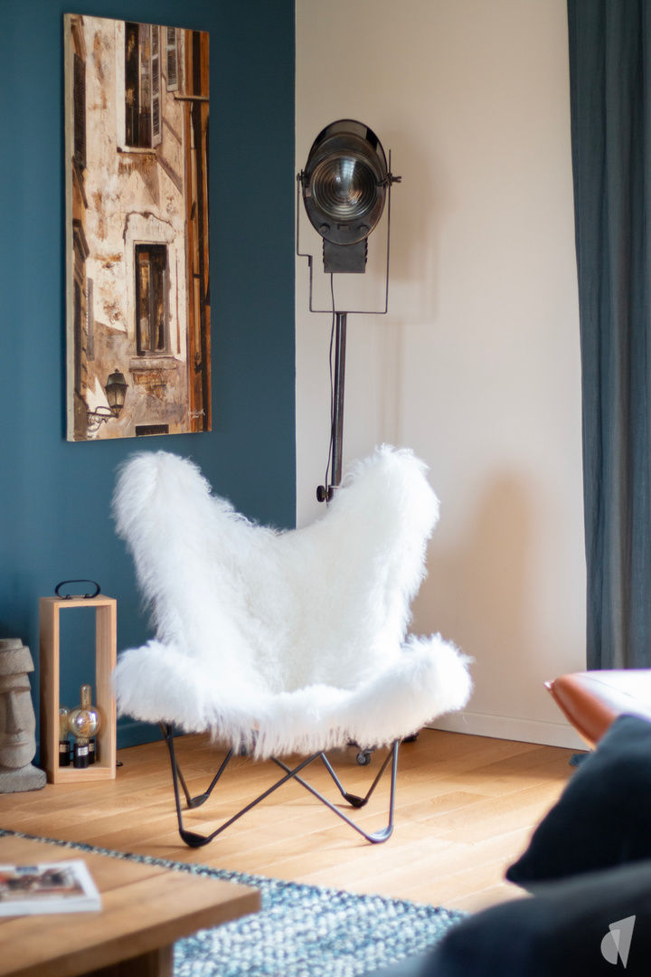 Décoration d'une pièce de vie au style industriel bleu à Aix les Bains, par Studio Coralie Vasseur : fauteuil papillon moumoute blanc