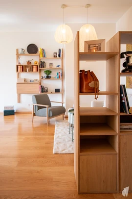 Décoration d'un appartement élégant en plein centre de Genève , par le Studio Coralie Vasseur. Coralie Vasseur est votre architecte d'intérieur et décoratrice UFDI à Annecy, Lyon, Chambéry et Grenoble : vue depuis l'entrée avec la bibliothèque séparative et le fauteuil vintage en tissu bouclettes