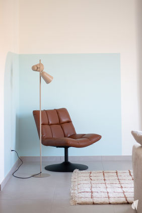 Décoration d'un appartement neuf pour location longue durée à Annecy-le-Vieux, par le Studio Coralie Vasseur. Coralie Vasseur est votre architecte d'intérieur et décoratrice  à Annecy : fauteuil design en cuir avec color zoning bleu au mur, pour coin lecture