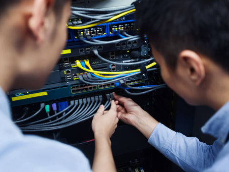 IT professionals setting up and managing network cables in a data center. AV subcontractor services ensuring seamless connectivity and enterprise network infrastructure support.
