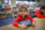 preschool student smiling at a desk with a tablet