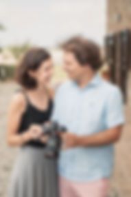 Casal de homem e mulher, se olhando e segurando uma câmera