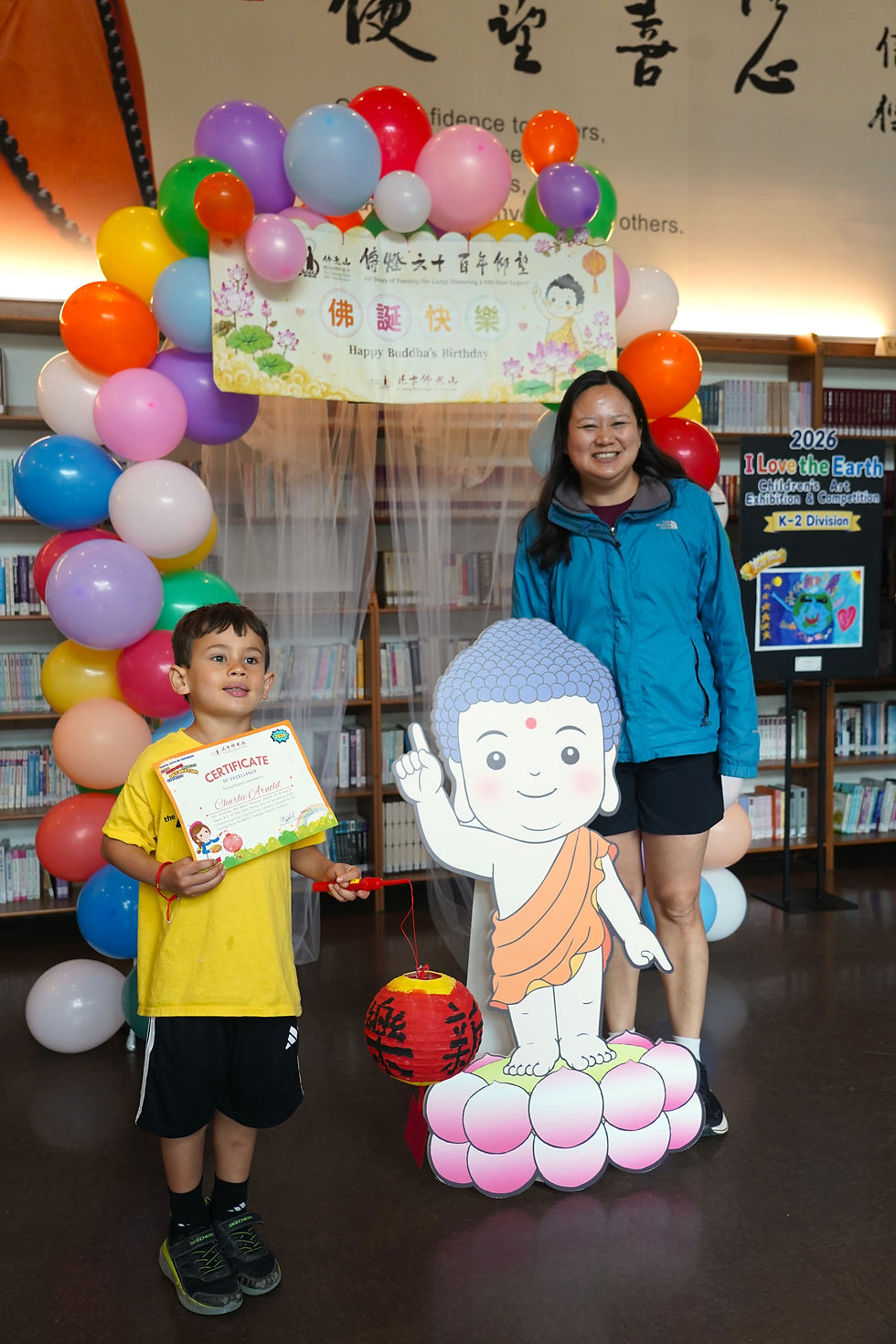 Children attending the award ceremony stop to take photos with the statue of Prince Siddhartha. (Photo by Wei Yixuan)