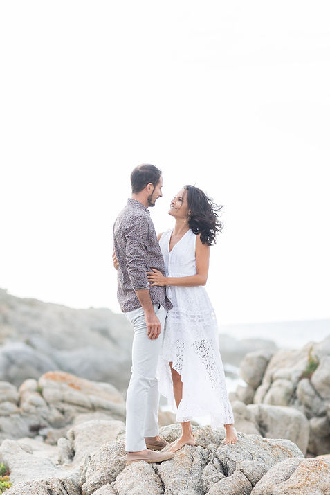 un couple se regarde tendrement pendant un moment romantique au de la mer sur des roché en Corse