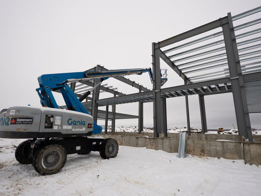 View of commercial steel building under construction in a winter setting.