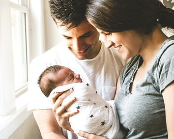 woman holding baby beside man smiling_ed