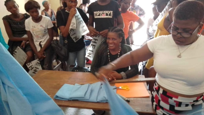 Photo of uniform fabric being distributed to the girls at the Lycee des jeunes filles du Cap-Haitien