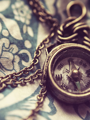 An old brass compass on a chain resting on vintage fabric, symbolising timeless guidance, self-reflection, and finding your path later in life.