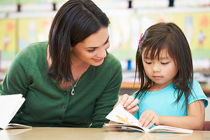Elementary Pupil Reading With Teacher In Classroom.jpg