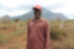 Kenyan man in a dry field in front of a large hill