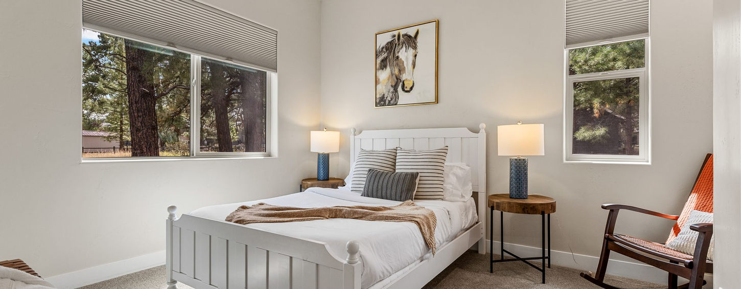 Bedroom with a white bed, bedside lamps and rocking chair