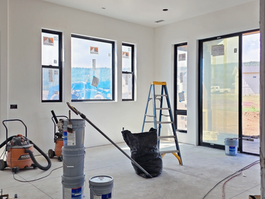 Room with windows, paint supplies, and equipment during interior finishing