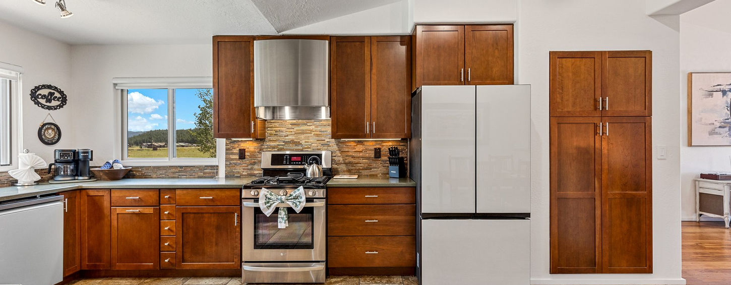 Fully equipped kitchen with wood cabinets, range with stainless hood and white refrigerator