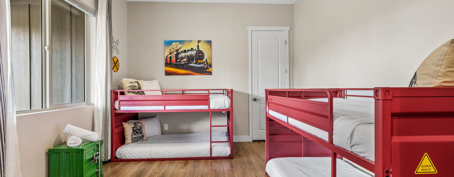 Bunk room with red metal bunk beds and train artwork