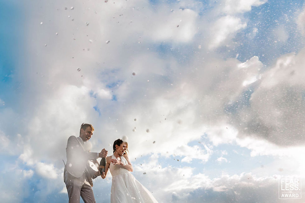 Wedding couple opening champagne beneath dramatic Irish sky