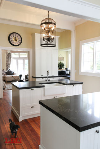 A small poodle wanders through a country style kitchen