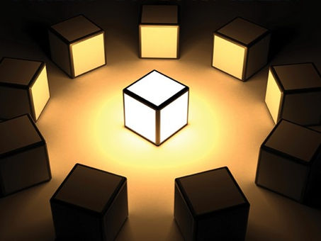 A glowing cube illuminated at the center, surrounded by darker cubes arranged in a circle, symbolizing leadership, focus, or innovation.
