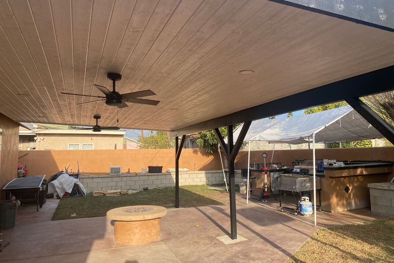 Completed solid patio cover with wood-grain ceiling, ceiling fans and finished concrete patio
