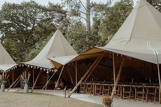 Giant tipis in a woodland setting with tables and chairs
