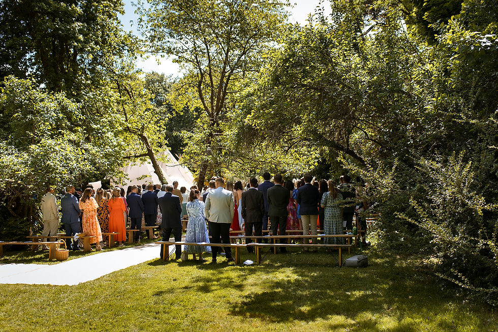 Wedding guests standing at outdoor ceremony in a beautiful garden in the summer