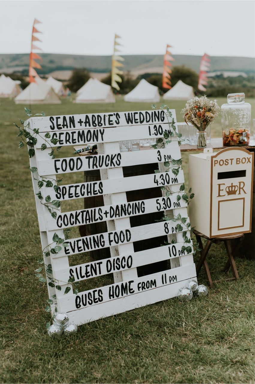 Rustic wedding sign in a field at a festival wedding