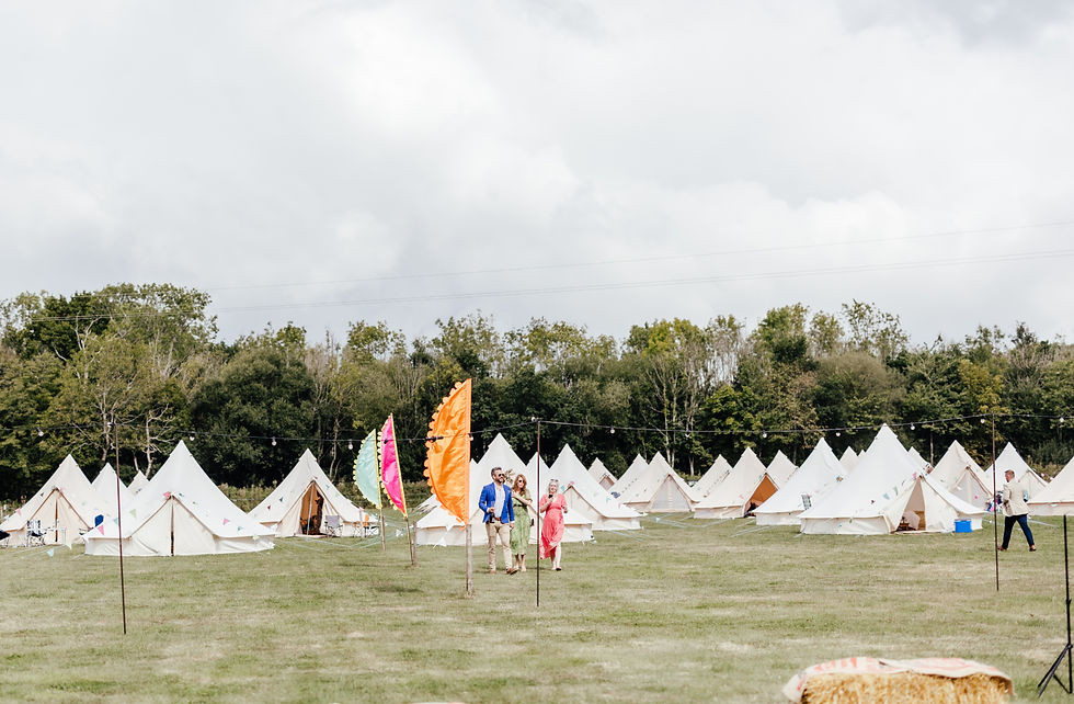 Wedding glamping village with bell tents, colourful festival flags and guests