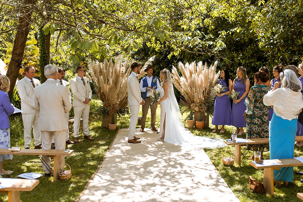 Boho garden wedding ceremony with bride, groom and celebrant exchanging vows with giant pampas floral displays
