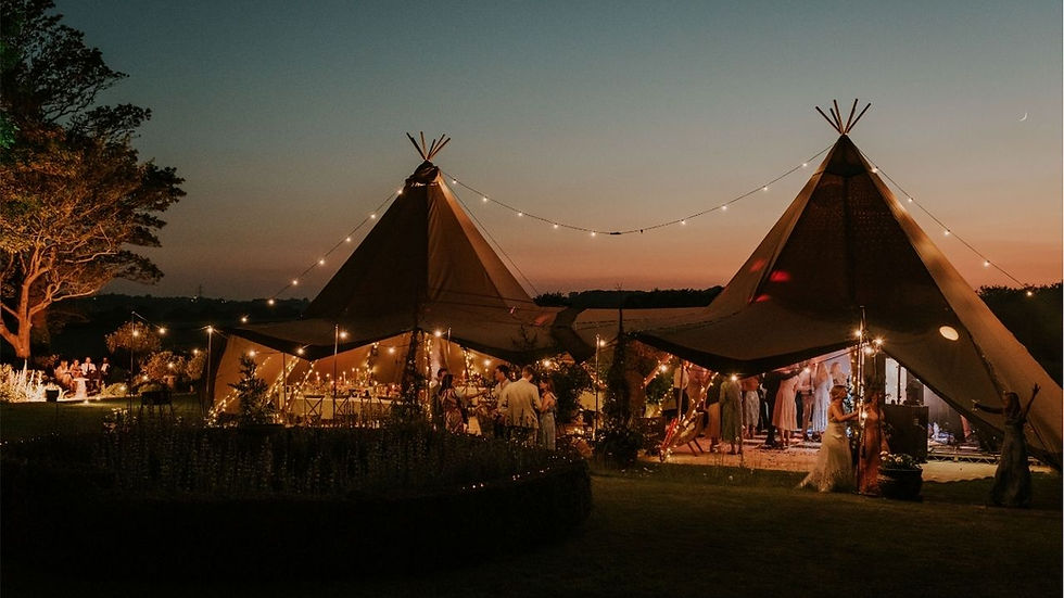 Tipi garden wedding at night with festoon lights and wedding guests dancing inside